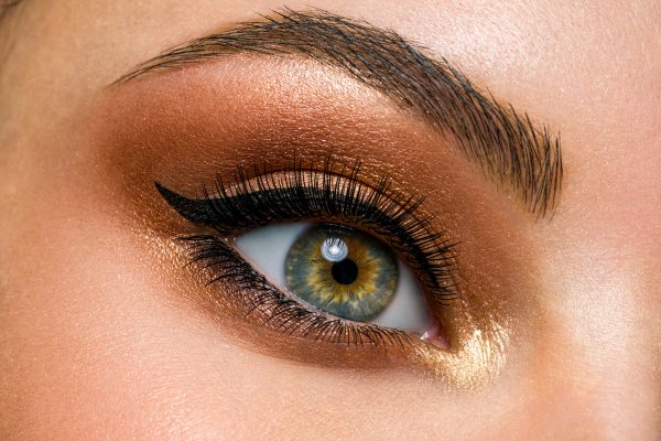 Beautiful female eye with brown, shiny makeup. Fashionable brown makeup. Macro image of a woman's eye.